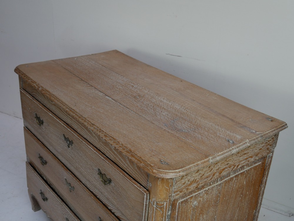 An 18th-century French provincial limed oak chest of drawers featuring three full-width drawers with brass handles and a scalloped apron. View V
