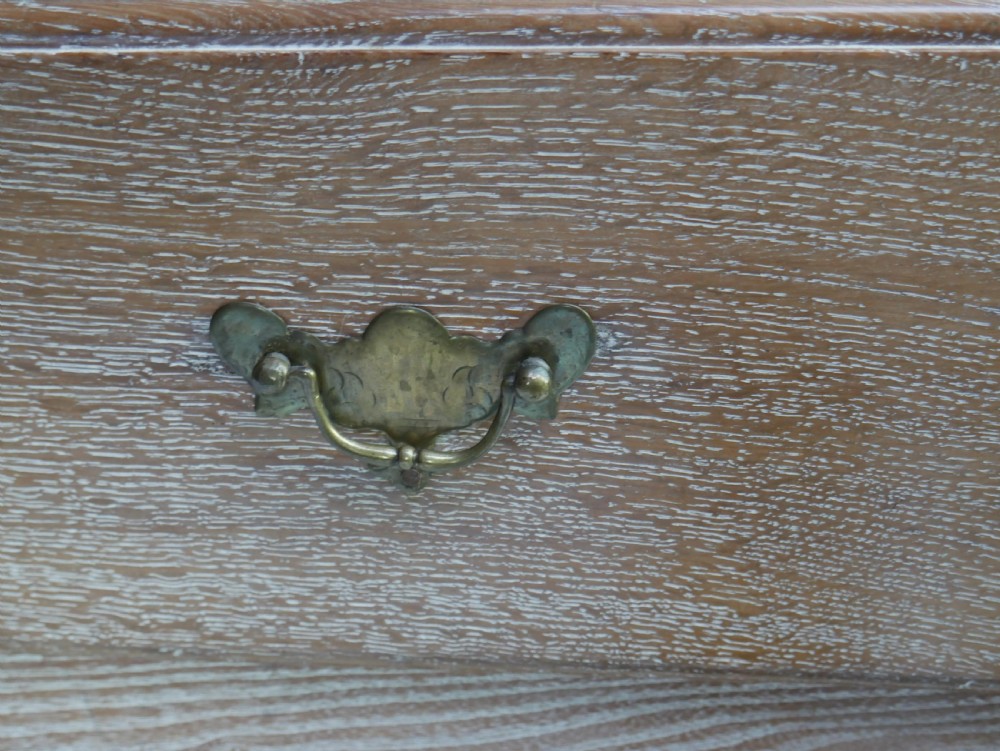 An 18th-century French provincial limed oak chest of drawers featuring three full-width drawers with brass handles and a scalloped apron. View VII