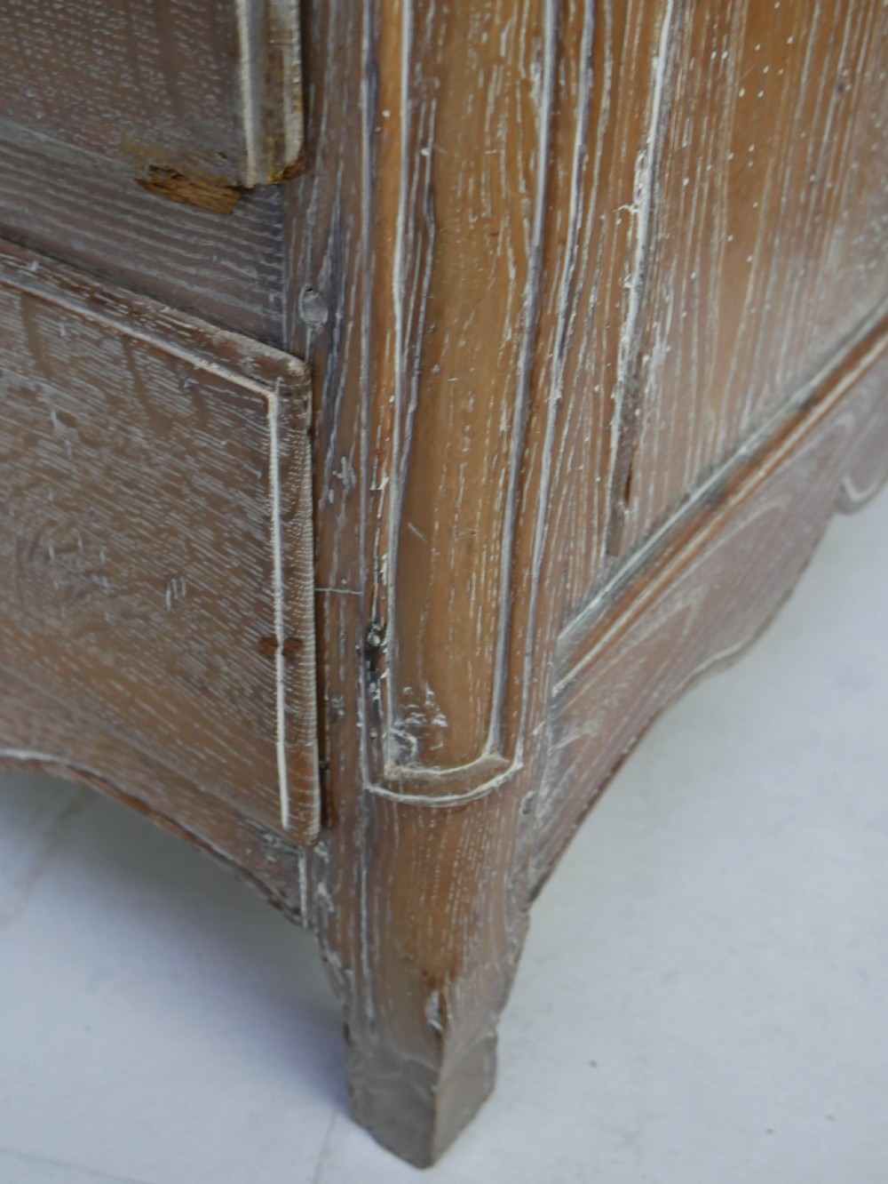 An 18th-century French provincial limed oak chest of drawers featuring three full-width drawers with brass handles and a scalloped apron. View XI