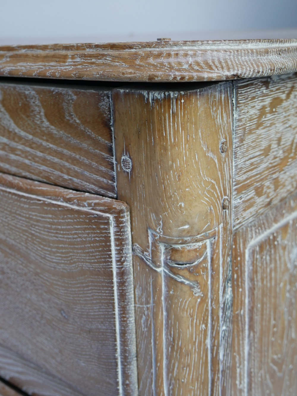 An 18th-century French provincial limed oak chest of drawers featuring three full-width drawers with brass handles and a scalloped apron. View XII