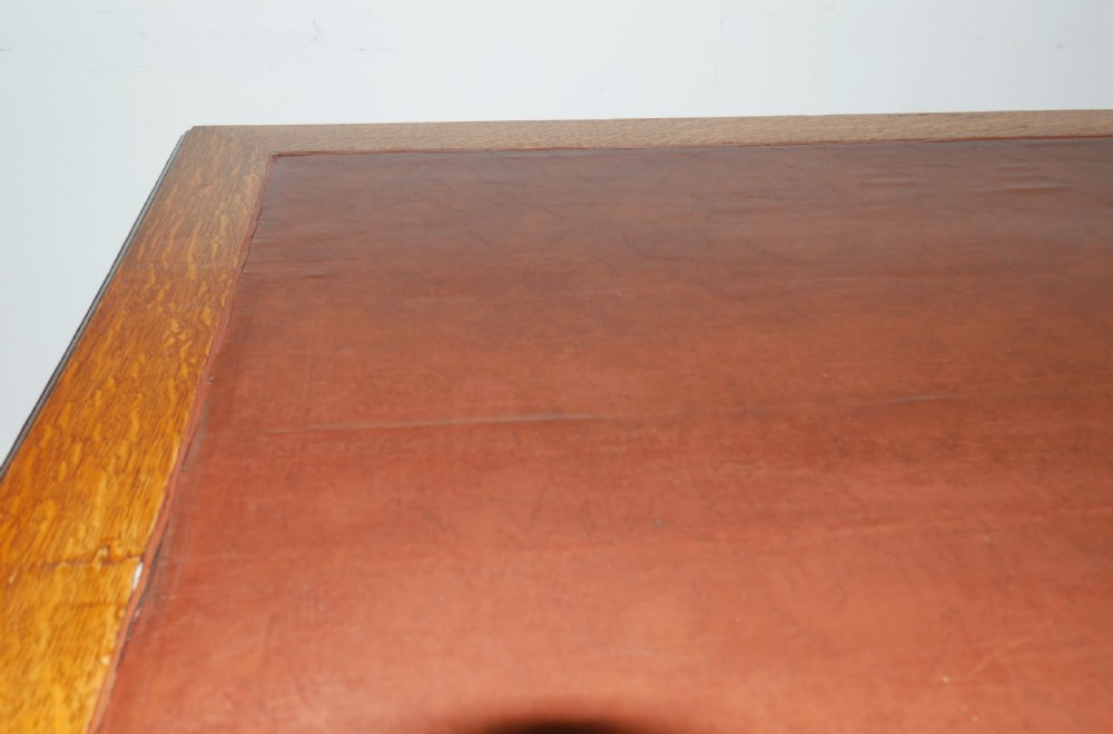 An antique oak partners kneehole desk featuring a leather-inset writing top, brass handles, and twin drawer pedestals on a plinth base. View VIII