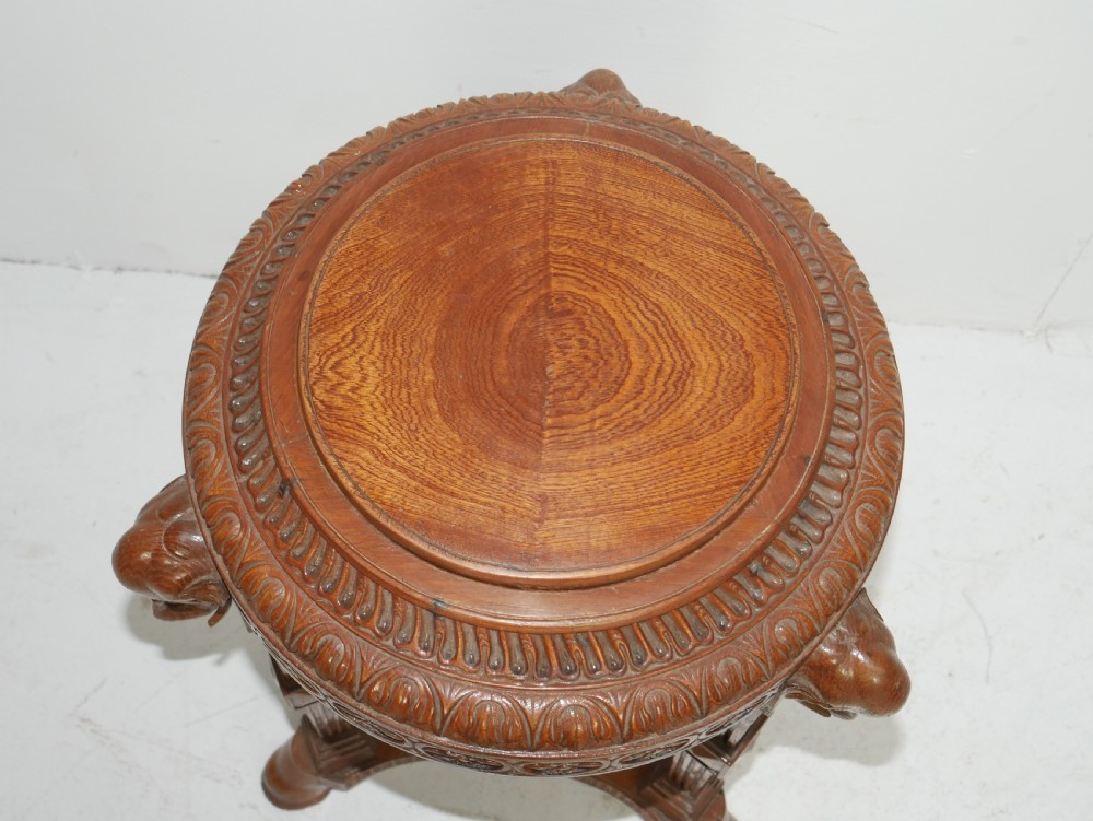 A circular Anglo-Indian carved hardwood plant stand supported by three fluted legs topped with carved elephant heads. View II