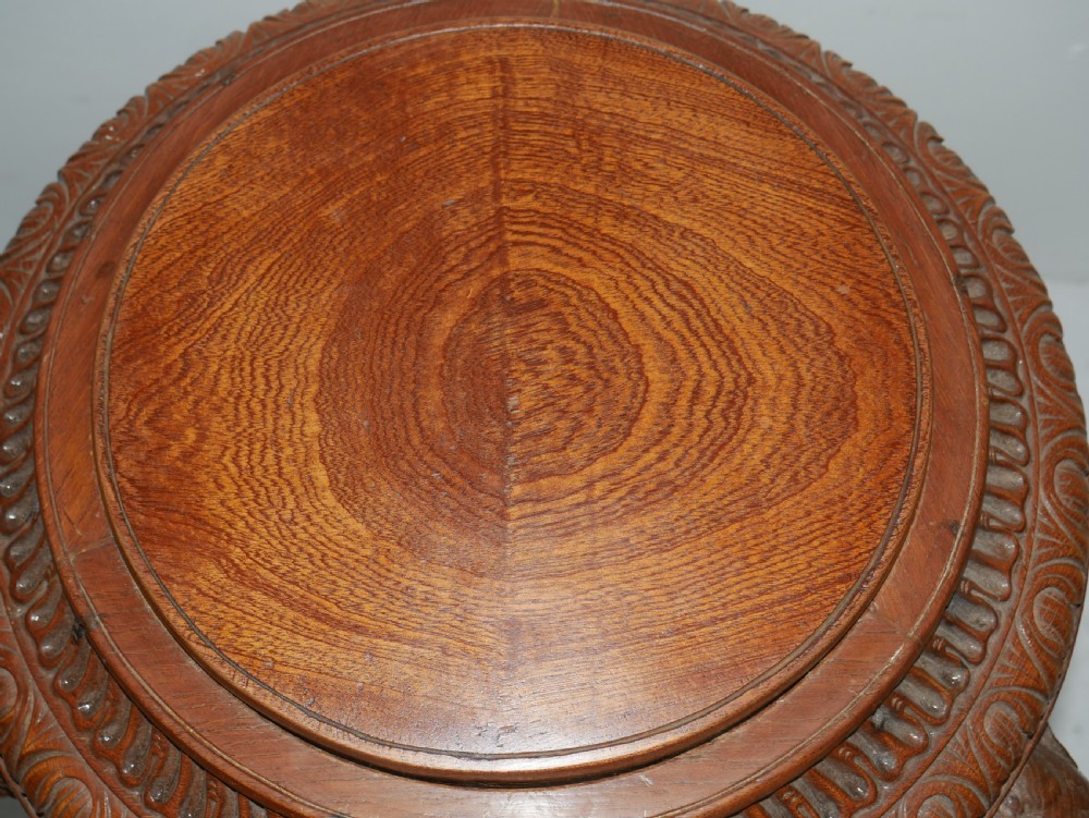 A circular Anglo-Indian carved hardwood plant stand supported by three fluted legs topped with carved elephant heads. View III