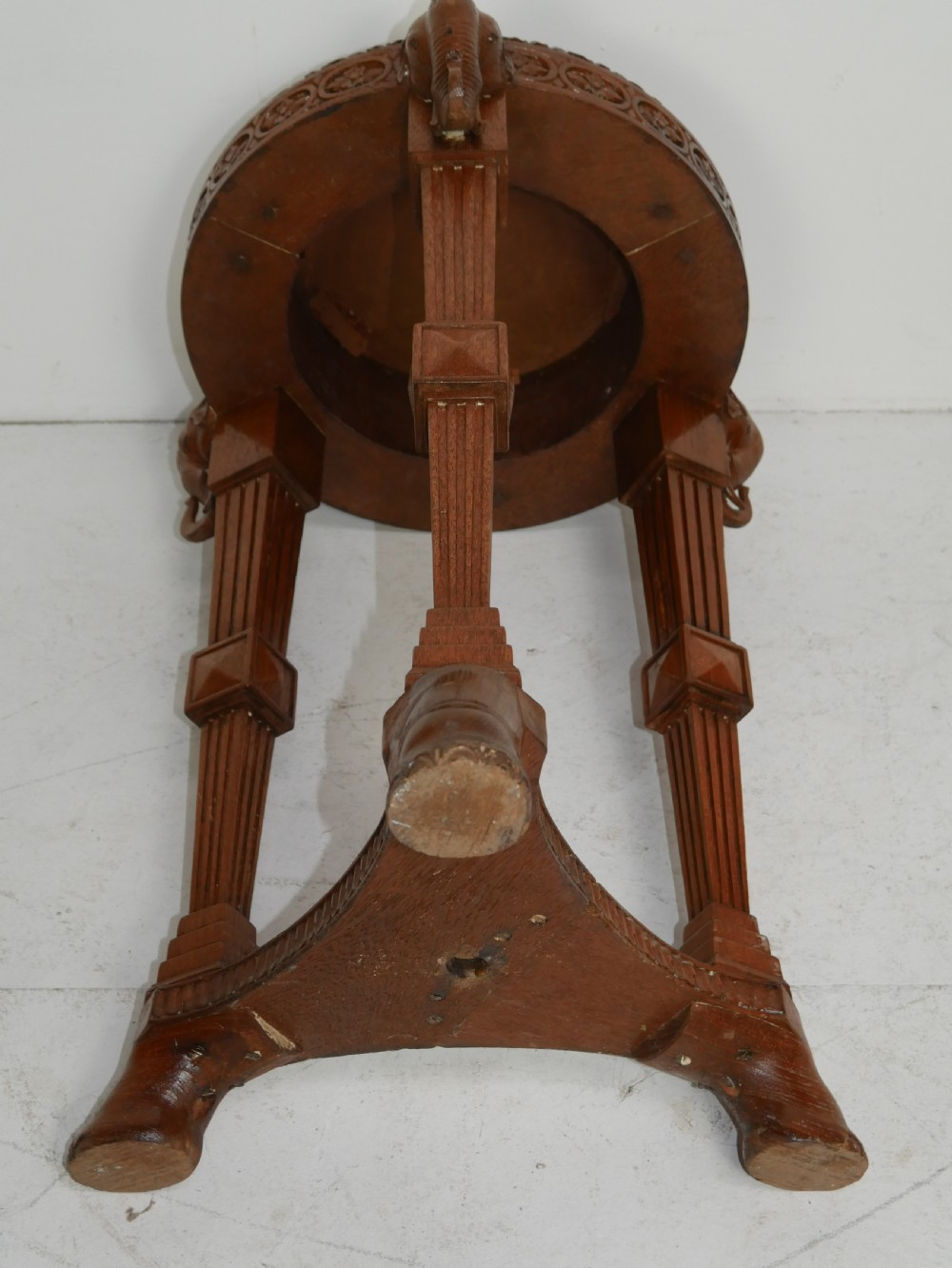 A circular Anglo-Indian carved hardwood plant stand supported by three fluted legs topped with carved elephant heads. View VII