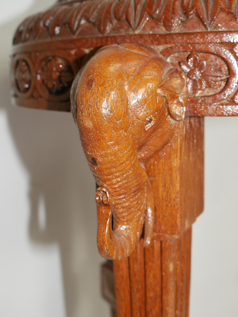 A circular Anglo-Indian carved hardwood plant stand supported by three fluted legs topped with carved elephant heads. View VIII