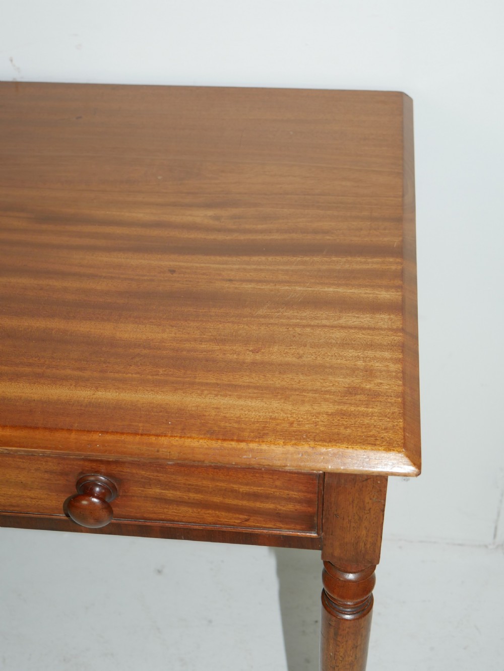A Regency mahogany writing table featuring a single drawer with two turned wooden knobs, supported by four slim turned tapered legs. View V