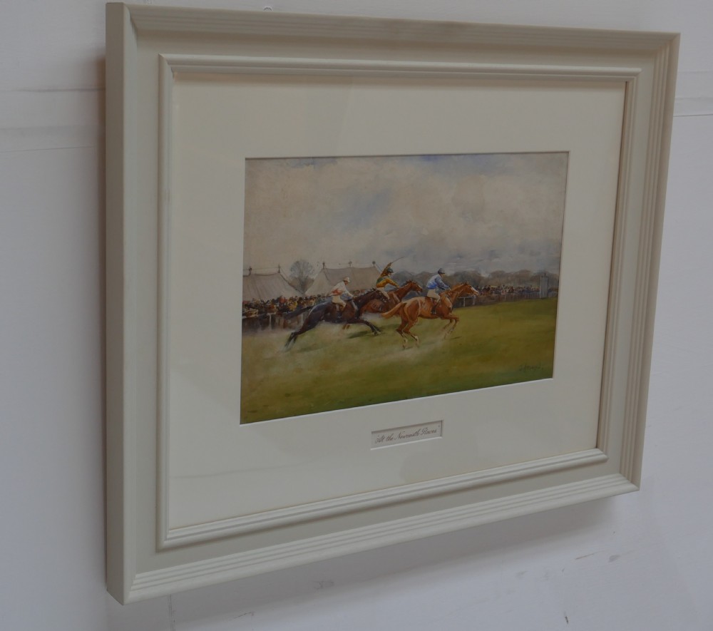 A framed watercolour painting depicting racehorses and jockeys galloping across a green field at the Newcastle races within an off-white moulded frame. View X