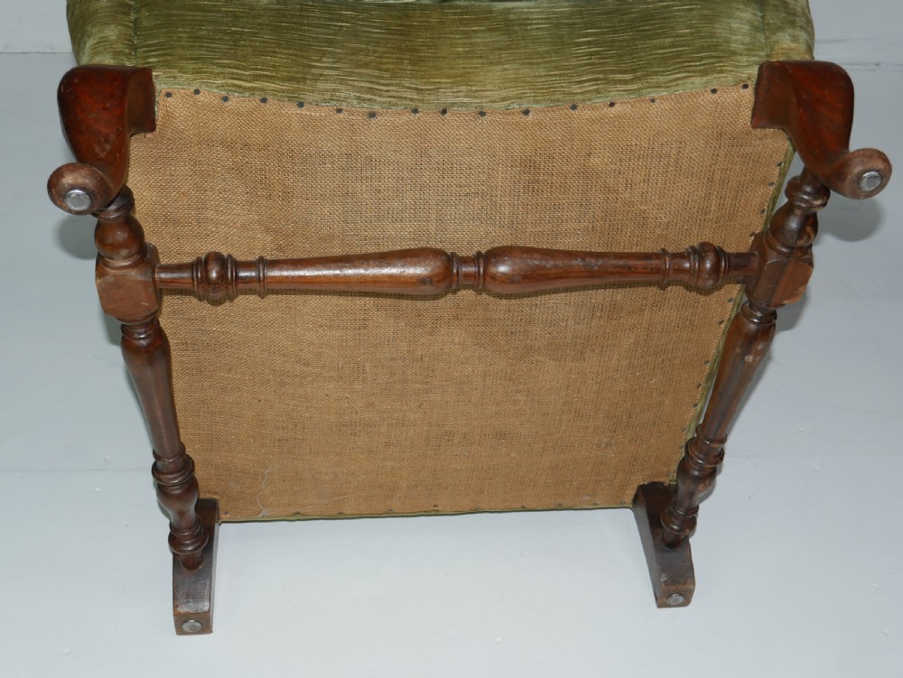 A high-backed wing armchair upholstered in textured olive green velvet with carved cabriole front legs and turned stretchers. View II