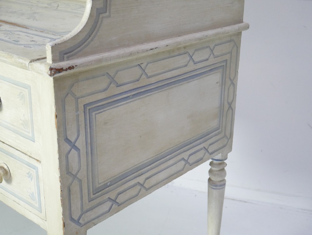 A 19th-century cream-painted wooden writing desk featuring five drawers, turned legs with stretchers, and a low gallery back decorated with light blue geometric painted borders. View III