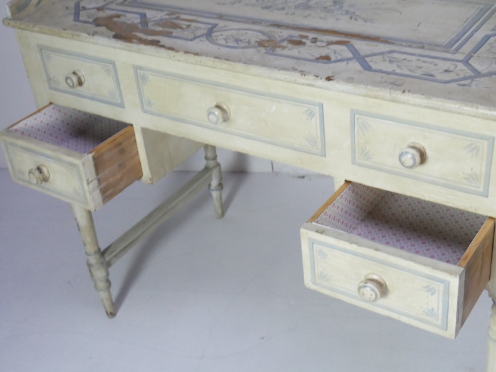 A 19th-century cream-painted wooden writing desk featuring five drawers, turned legs with stretchers, and a low gallery back decorated with light blue geometric painted borders. View XI