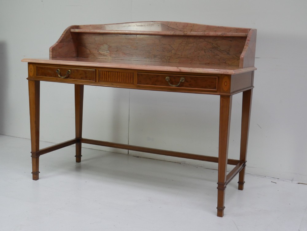 A mahogany writing table featuring two inlaid drawers, square tapered legs, and a pink marble top with a raised gallery back.