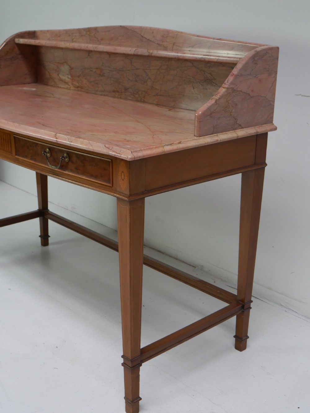A mahogany writing table featuring two inlaid drawers, square tapered legs, and a pink marble top with a raised gallery back. View V