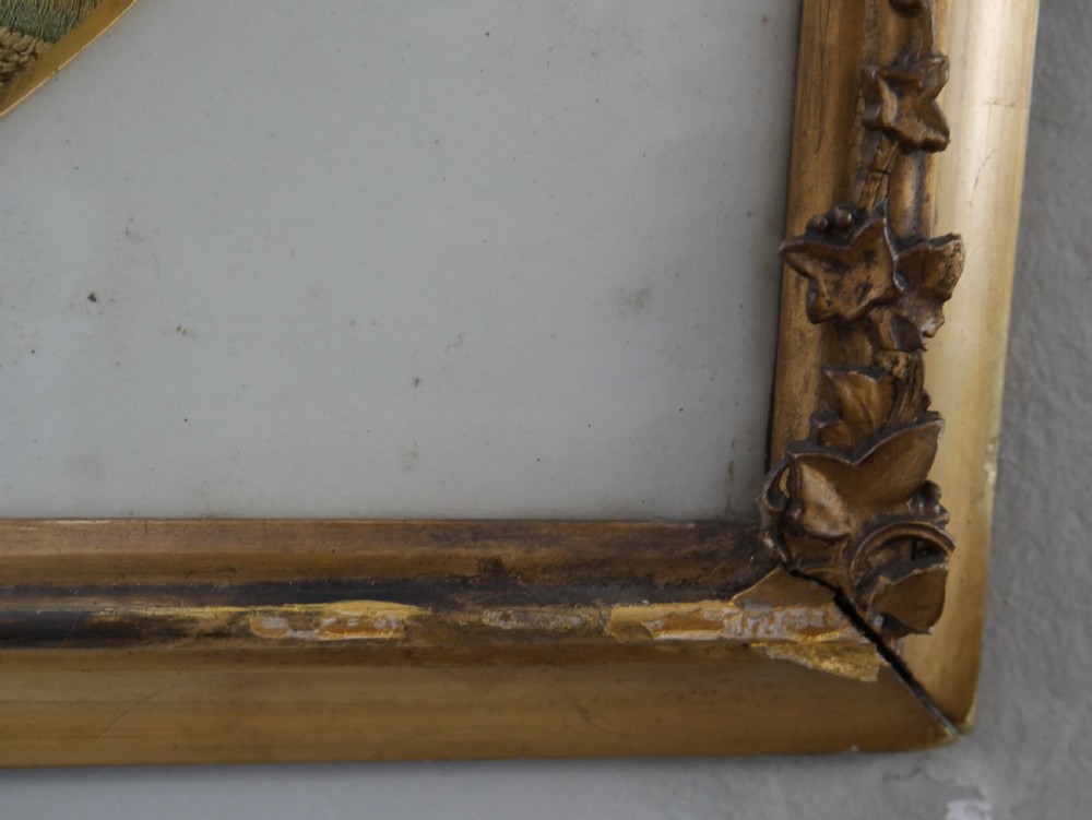 An early nineteenth-century oval crewel work embroidery depicting a shepherdess under a tree with sheep, set in a carved giltwood frame. View VII