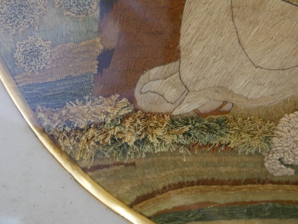An early nineteenth-century oval crewel work embroidery depicting a shepherdess under a tree with sheep, set in a carved giltwood frame. View VIII