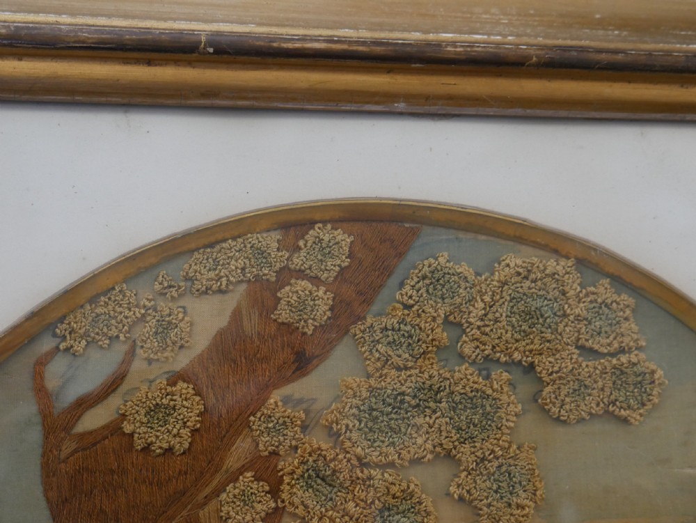 An early nineteenth-century oval crewel work embroidery depicting a shepherdess under a tree with sheep, set in a carved giltwood frame. View IX
