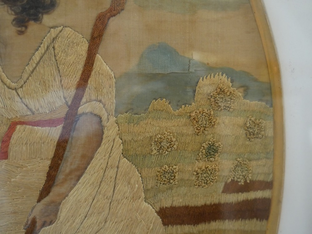 An early nineteenth-century oval crewel work embroidery depicting a shepherdess under a tree with sheep, set in a carved giltwood frame. View XI