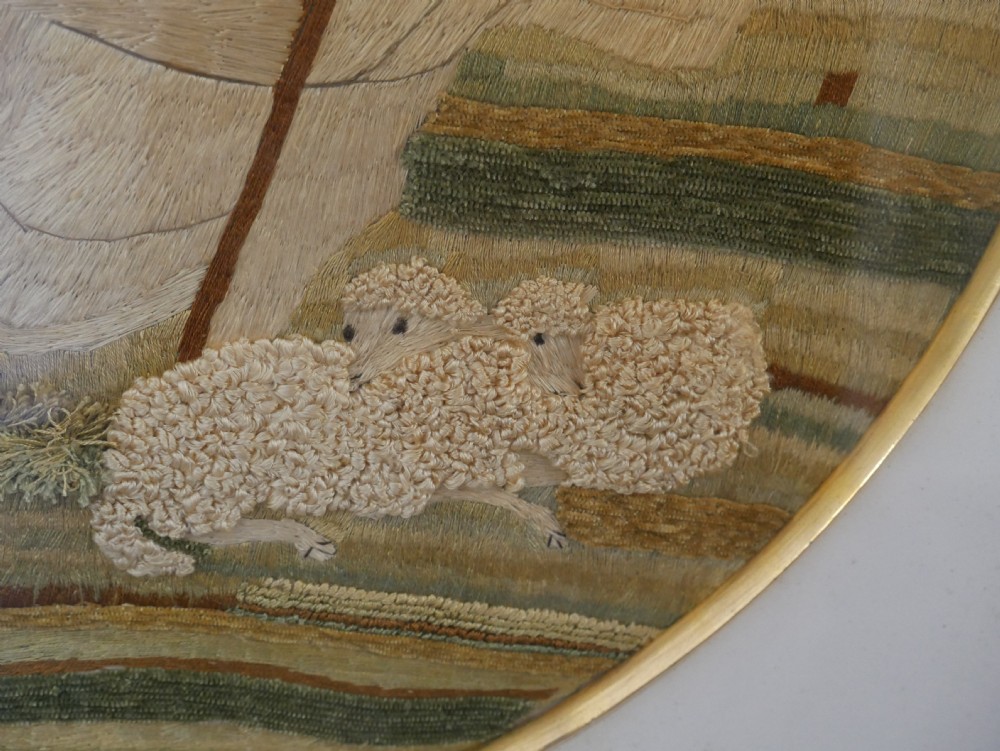 An early nineteenth-century oval crewel work embroidery depicting a shepherdess under a tree with sheep, set in a carved giltwood frame. View XII
