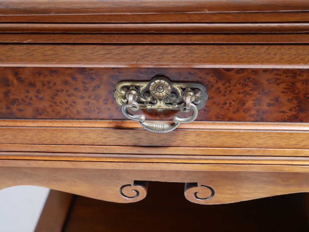 A late Victorian walnut and amboyna mirrored-back sideboard featuring carved panel doors, open tier shelving, turned spindles, and top finials. View V