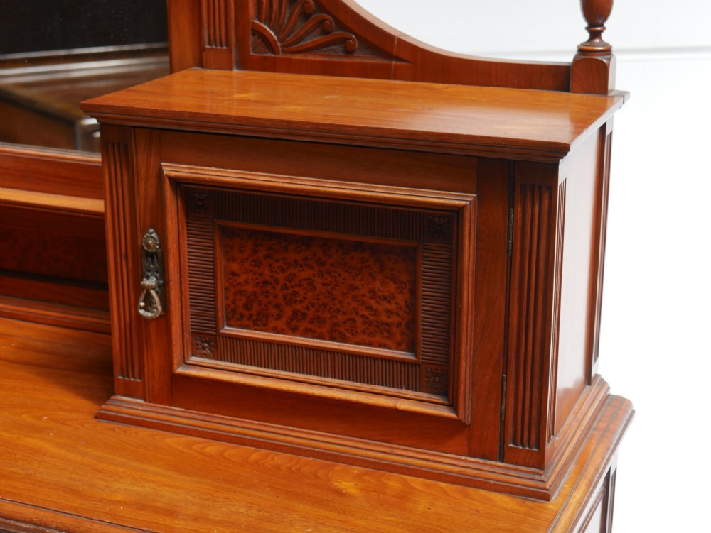 A late Victorian walnut and amboyna mirrored-back sideboard featuring carved panel doors, open tier shelving, turned spindles, and top finials. View VIII