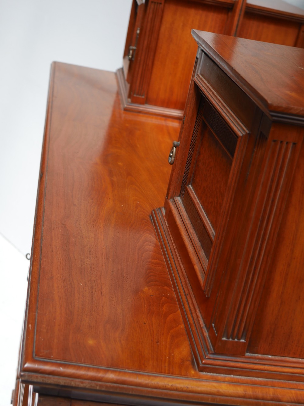 A late Victorian walnut and amboyna mirrored-back sideboard featuring carved panel doors, open tier shelving, turned spindles, and top finials. View IX