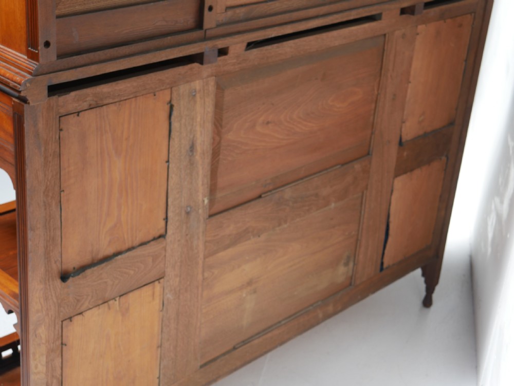 A late Victorian walnut and amboyna mirrored-back sideboard featuring carved panel doors, open tier shelving, turned spindles, and top finials. View XIV
