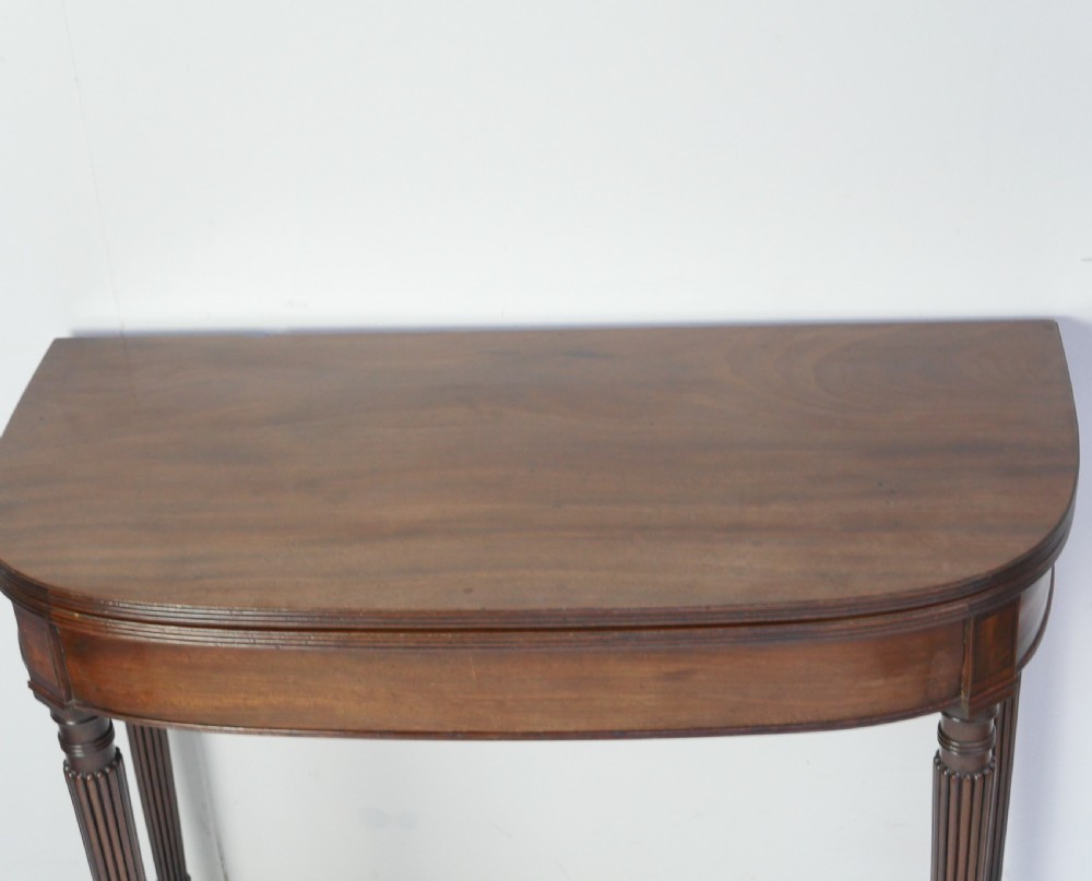 A Regency mahogany fold-over table featuring a demilune top, reeded legs, and brass castors. View III