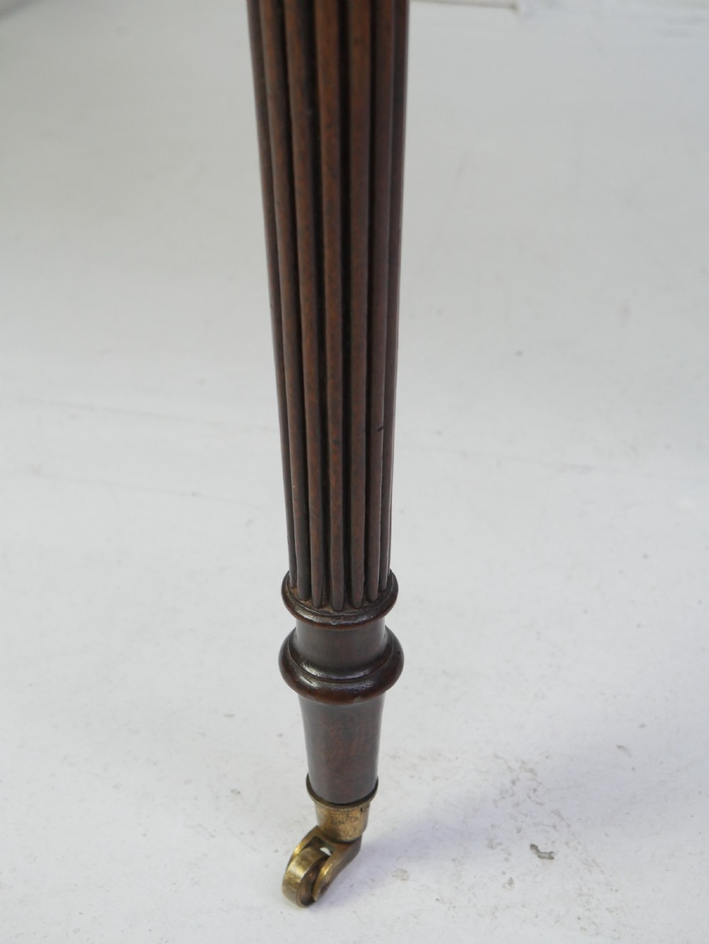 A Regency mahogany fold-over table featuring a demilune top, reeded legs, and brass castors. View VI