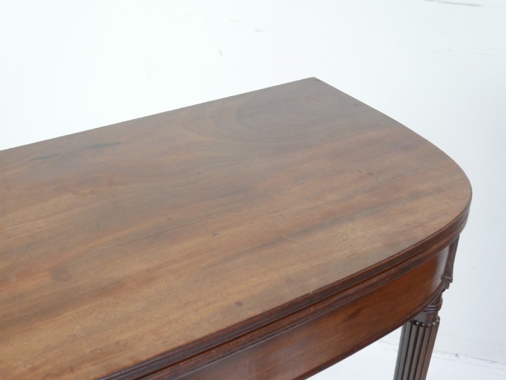 A Regency mahogany fold-over table featuring a demilune top, reeded legs, and brass castors. View XI