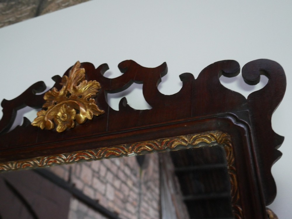 A rectangular Georgian mahogany wall mirror featuring a scroll-cut fretwork frame ornamented with giltwood leaves and cresting. View II