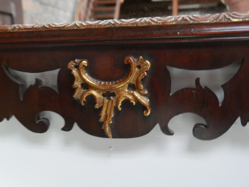 A rectangular Georgian mahogany wall mirror featuring a scroll-cut fretwork frame ornamented with giltwood leaves and cresting. View VI