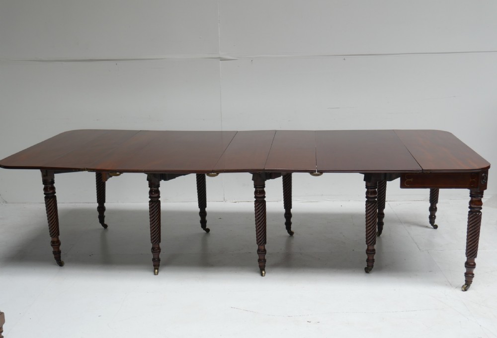 A large antique mahogany extending dining table featuring spiral-turned legs and fitted brass castors.