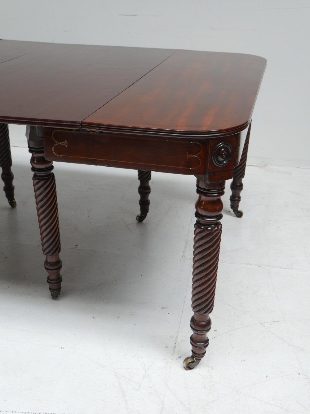 A large antique mahogany extending dining table featuring spiral-turned legs and fitted brass castors. View II