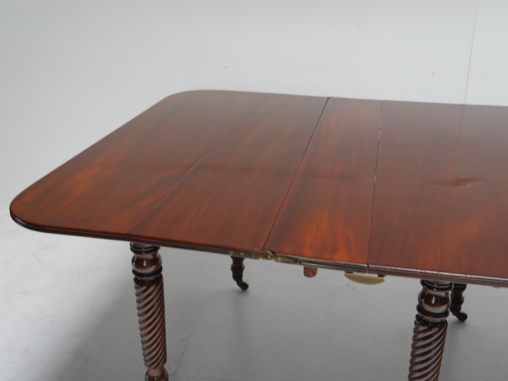A large antique mahogany extending dining table featuring spiral-turned legs and fitted brass castors. View IX
