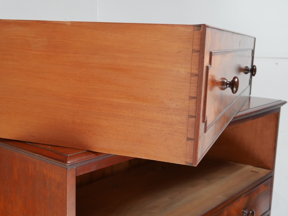 A classic Regency mahogany chest featuring four horizontal drawers with flame mahogany grain, turned wooden knobs, brass keyhole escutcheons, and turned feet. View III