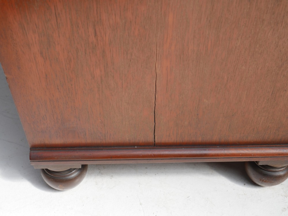 A classic Regency mahogany chest featuring four horizontal drawers with flame mahogany grain, turned wooden knobs, brass keyhole escutcheons, and turned feet. View VI