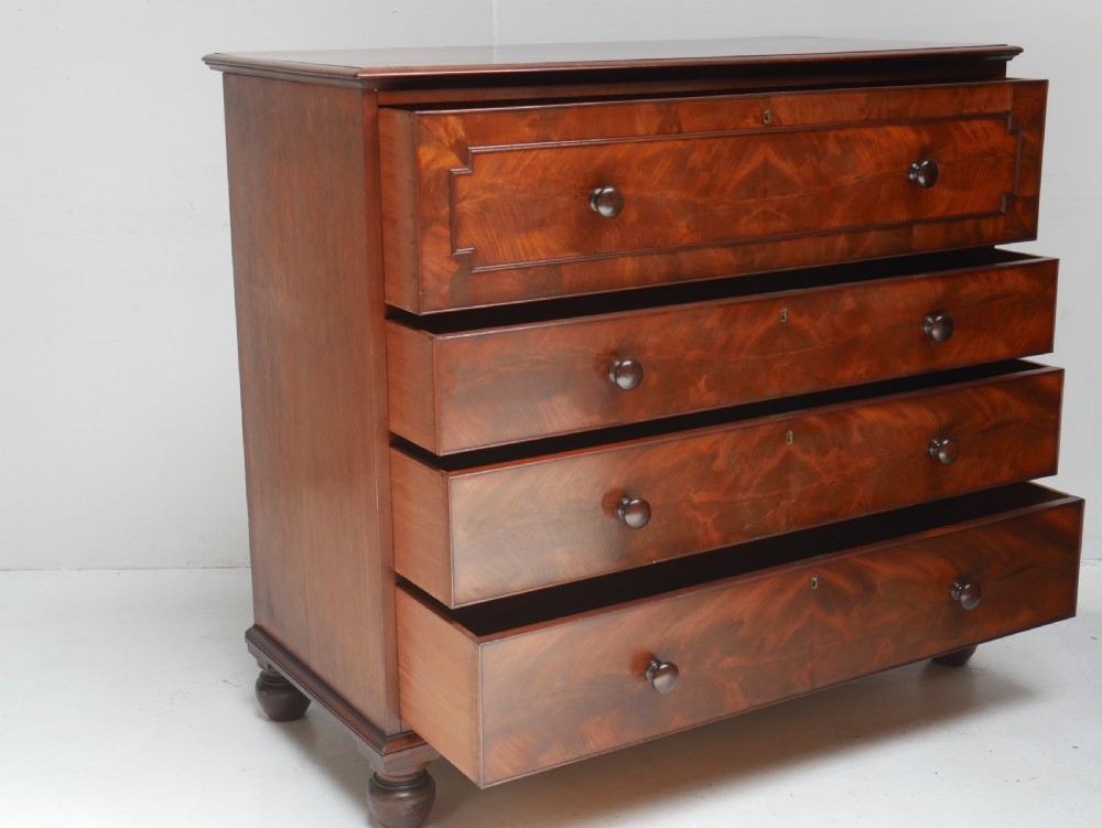 A classic Regency mahogany chest featuring four horizontal drawers with flame mahogany grain, turned wooden knobs, brass keyhole escutcheons, and turned feet. View X