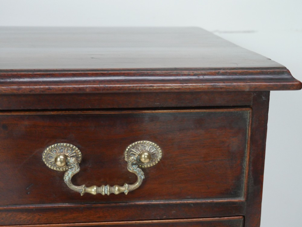 A Georgian mahogany chest of drawers featuring four graduated drawers with brass swan-neck handles and bracket feet. View II