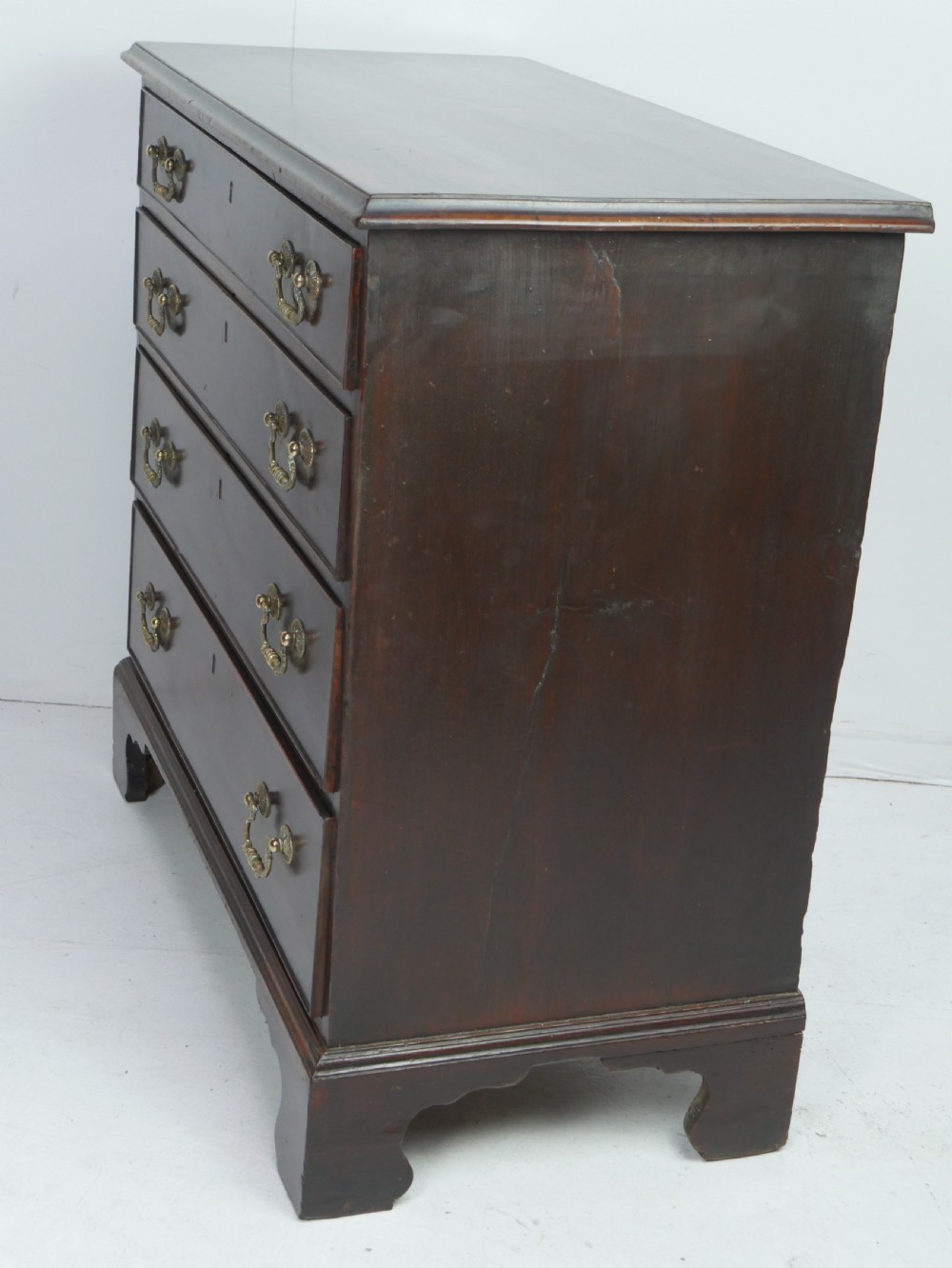 A Georgian mahogany chest of drawers featuring four graduated drawers with brass swan-neck handles and bracket feet. View VI