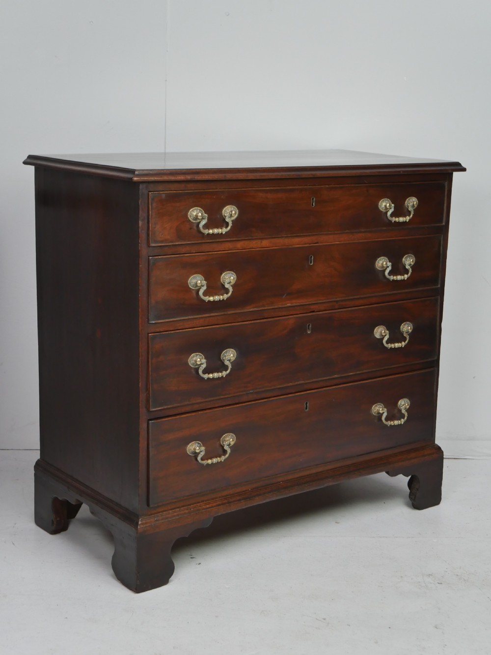 A Georgian mahogany chest of drawers featuring four graduated drawers with brass swan-neck handles and bracket feet. View IX