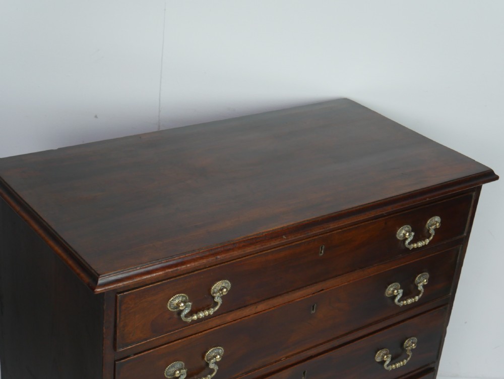 A Georgian mahogany chest of drawers featuring four graduated drawers with brass swan-neck handles and bracket feet. View X