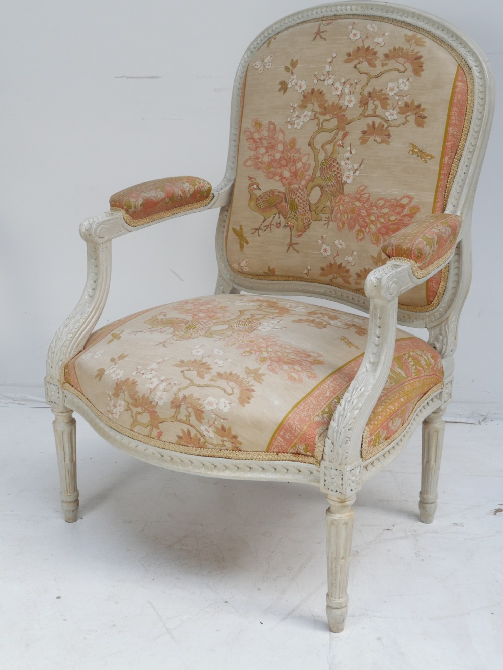 A pair of French Louis XVI style fauteuil armchairs featuring off-white painted frames, fluted legs, and patterned floral upholstery. View II