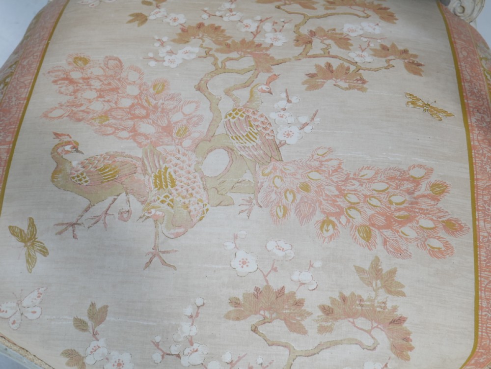A pair of French Louis XVI style fauteuil armchairs featuring off-white painted frames, fluted legs, and patterned floral upholstery. View V