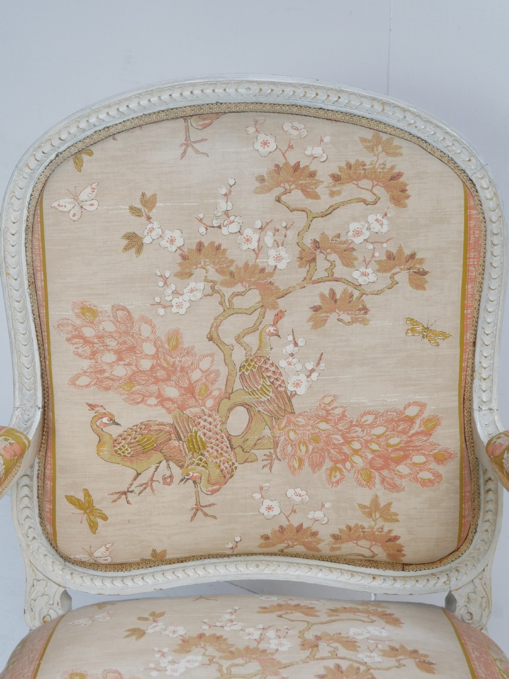 A pair of French Louis XVI style fauteuil armchairs featuring off-white painted frames, fluted legs, and patterned floral upholstery. View VI