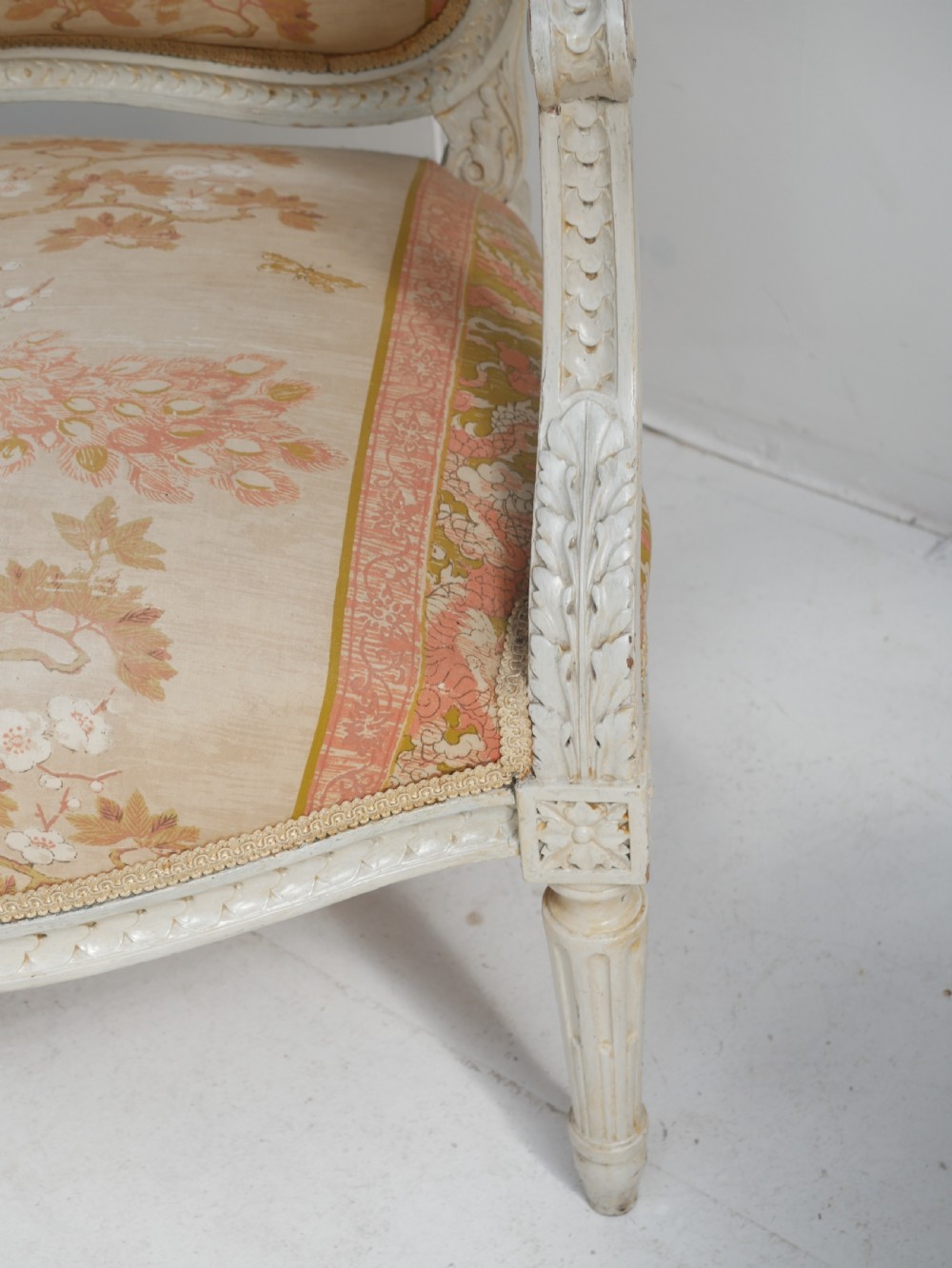A pair of French Louis XVI style fauteuil armchairs featuring off-white painted frames, fluted legs, and patterned floral upholstery. View VII