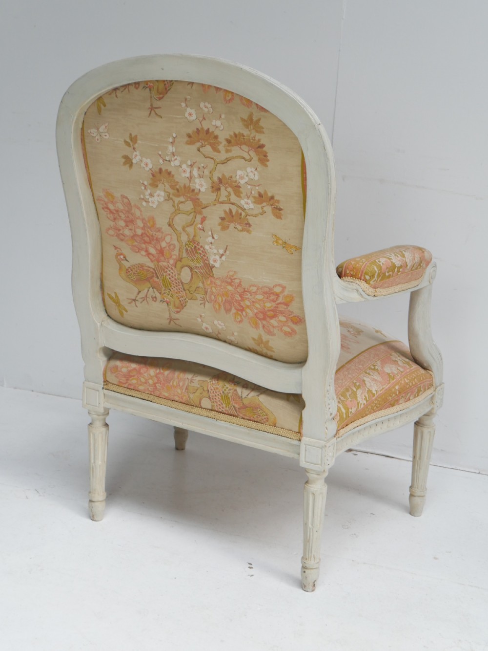 A pair of French Louis XVI style fauteuil armchairs featuring off-white painted frames, fluted legs, and patterned floral upholstery. View IX