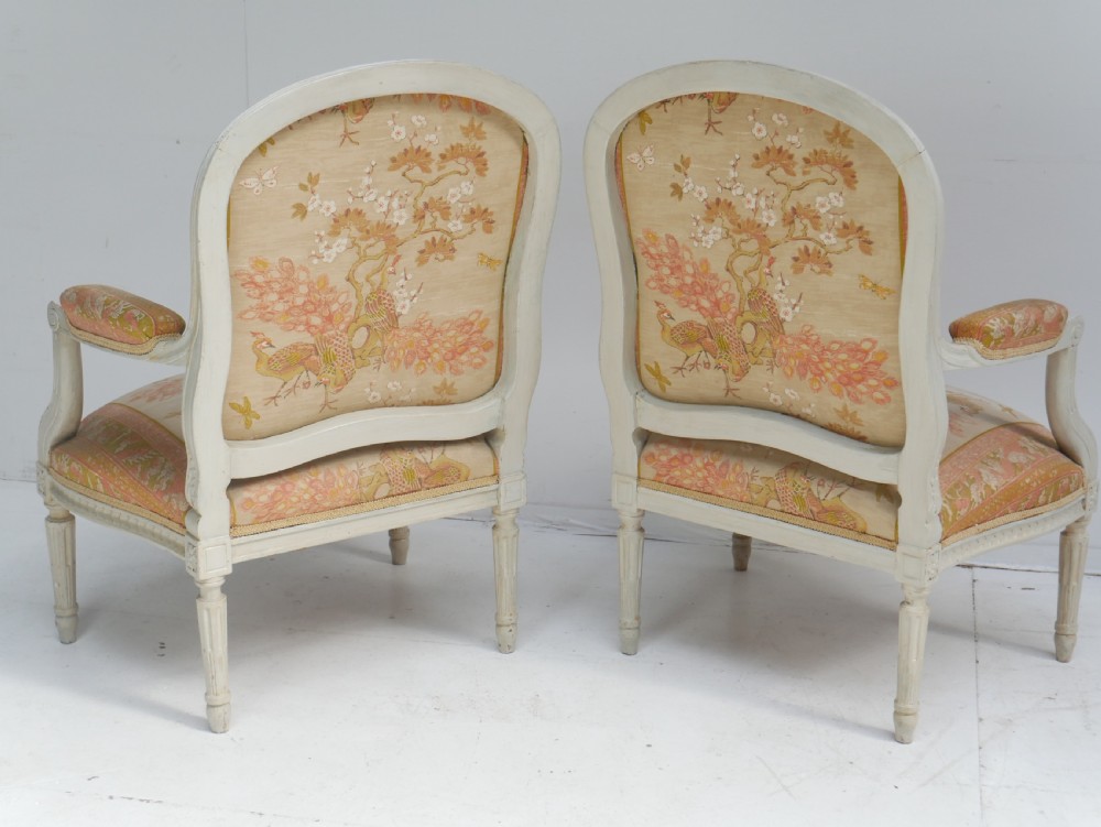 A pair of French Louis XVI style fauteuil armchairs featuring off-white painted frames, fluted legs, and patterned floral upholstery. View XI