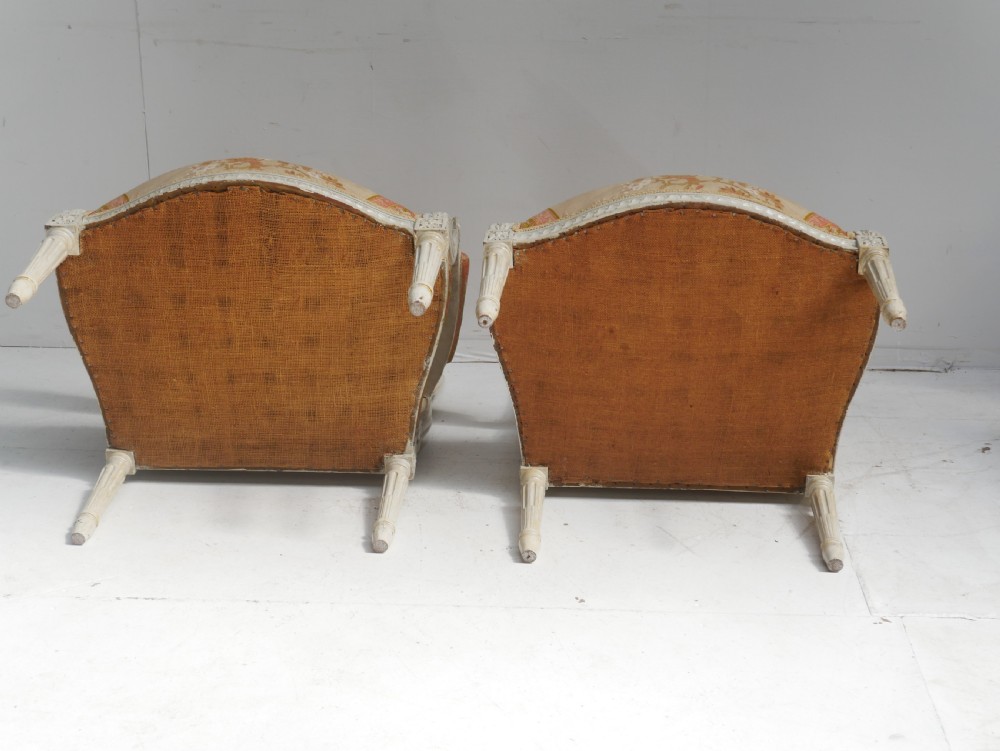 A pair of French Louis XVI style fauteuil armchairs featuring off-white painted frames, fluted legs, and patterned floral upholstery. View XII