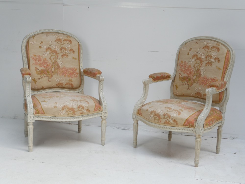 A pair of French Louis XVI style fauteuil armchairs featuring off-white painted frames, fluted legs, and patterned floral upholstery. View XIII
