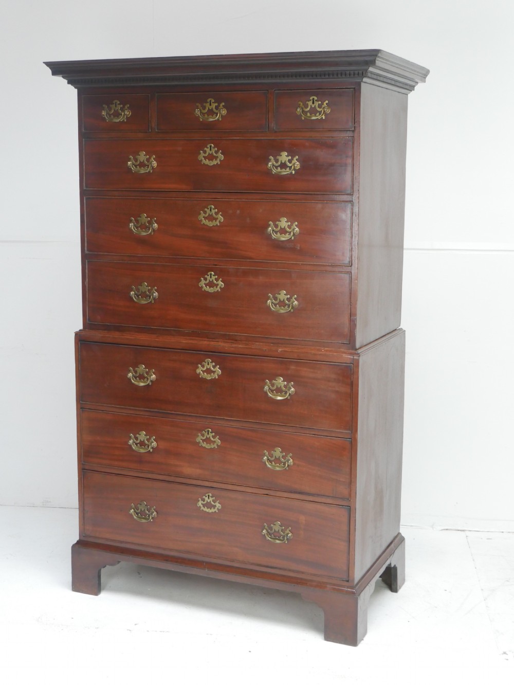 An eighteenth-century Georgian dark mahogany secretaire tallboy featuring two stacked chest sections, brass handles, and bracket feet. View XVIII