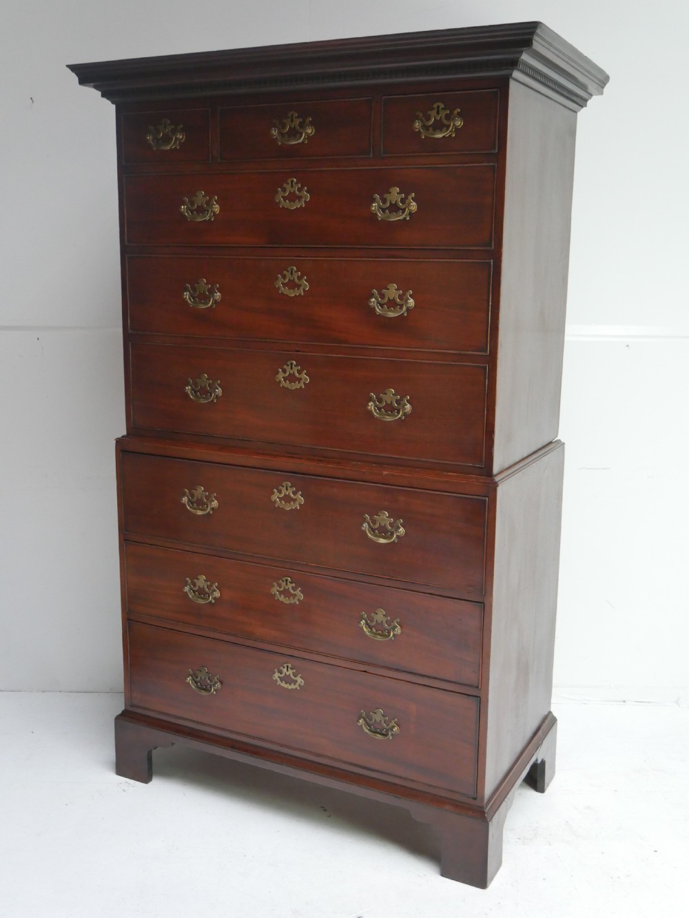 An eighteenth-century Georgian dark mahogany secretaire tallboy featuring two stacked chest sections, brass handles, and bracket feet.